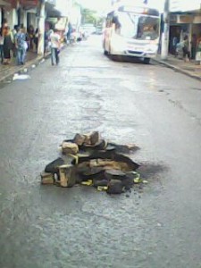 Buraco pode virar uma cratera em frente ao número 511 da Rua do Comércio, principal corredor de ônibus. (Foto celular : Warner Oliveira)