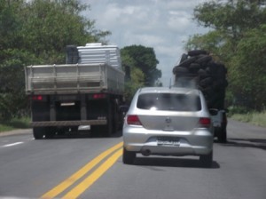 Carga perigosa e além da altura permitida (carro transportando pneus), além da ultrapassagem ilegal do caminhão. (Foto : Warner Oliveira)